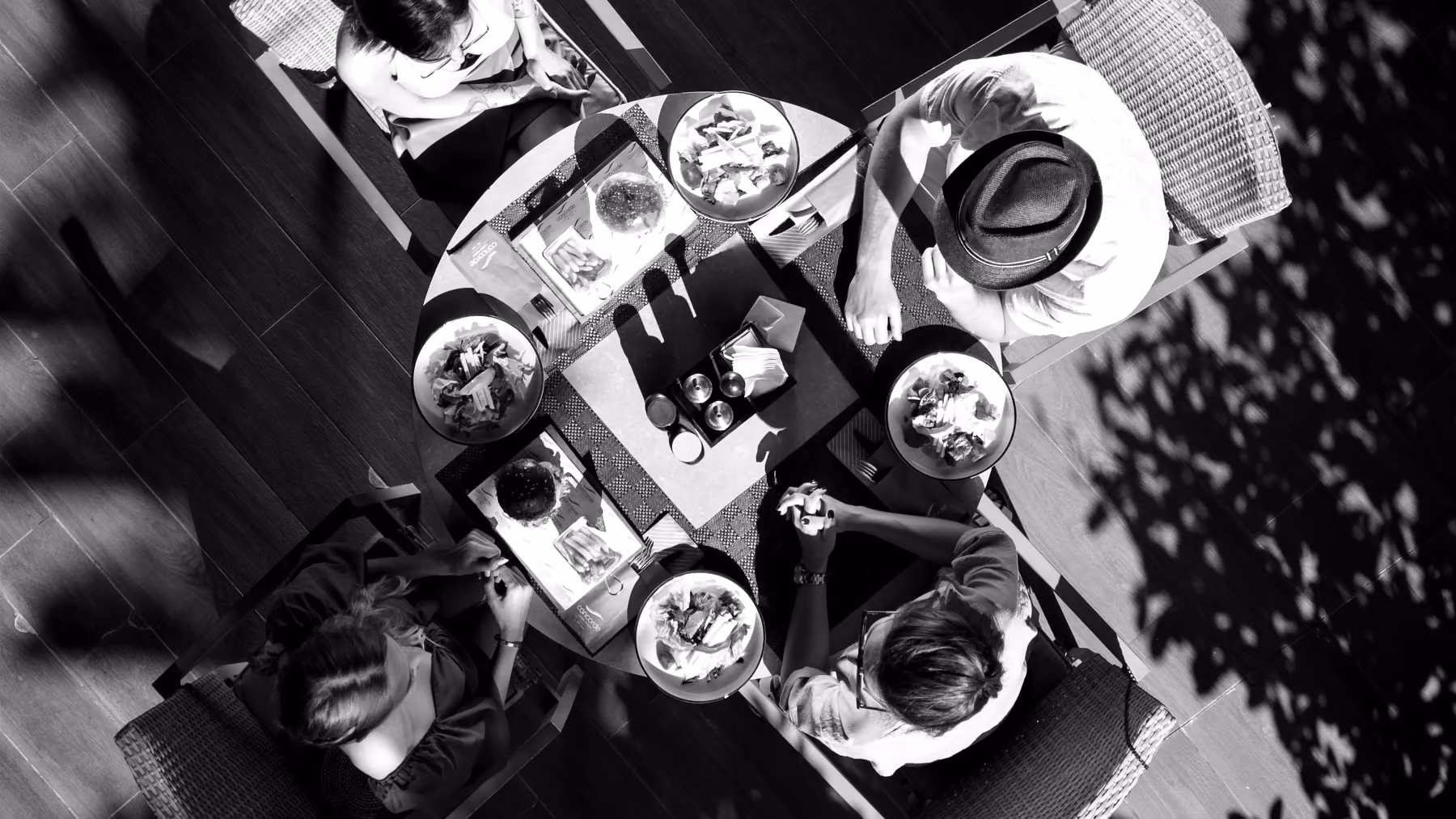 Table ronde vue de haut, quatre personnes attablées, en noir et blanc
