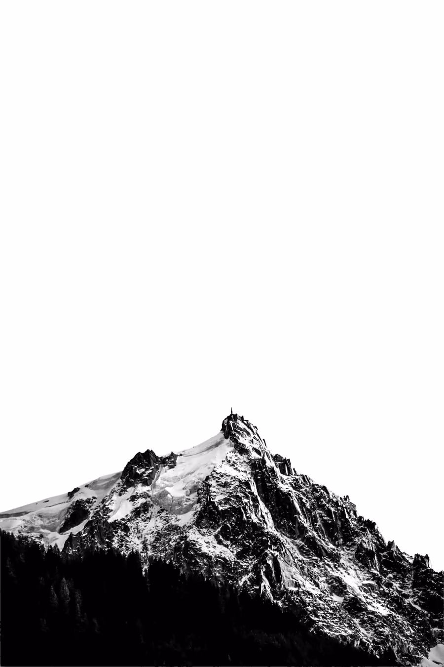 Snowy peak and rocky ridge above a forest, in black and white